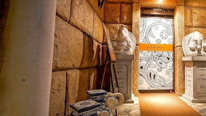 Un vestíbulo de hotel con paredes de piedra, una estatua y una puerta con diseño.