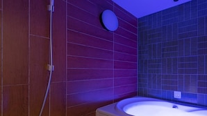Un baño moderno con pared de madera, un espejo redondo y una bañera.