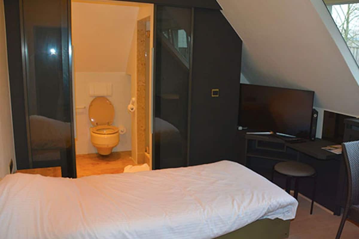 Un dormitorio con cama, escritorio y televisor.