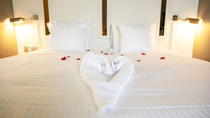 A neatly made bed with a heart-shaped towel and scattered rose petals. - Hostellerie Klokhof (Kortrijk)