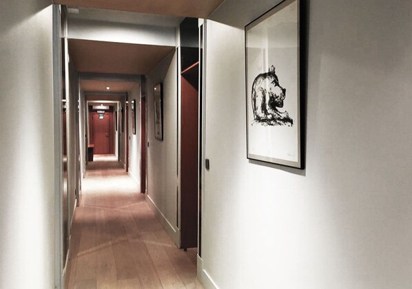A hallway with a wooden floor, a framed picture on the wall, and doors leading to other rooms. - Hostellerie Klokhof (Kortrijk)