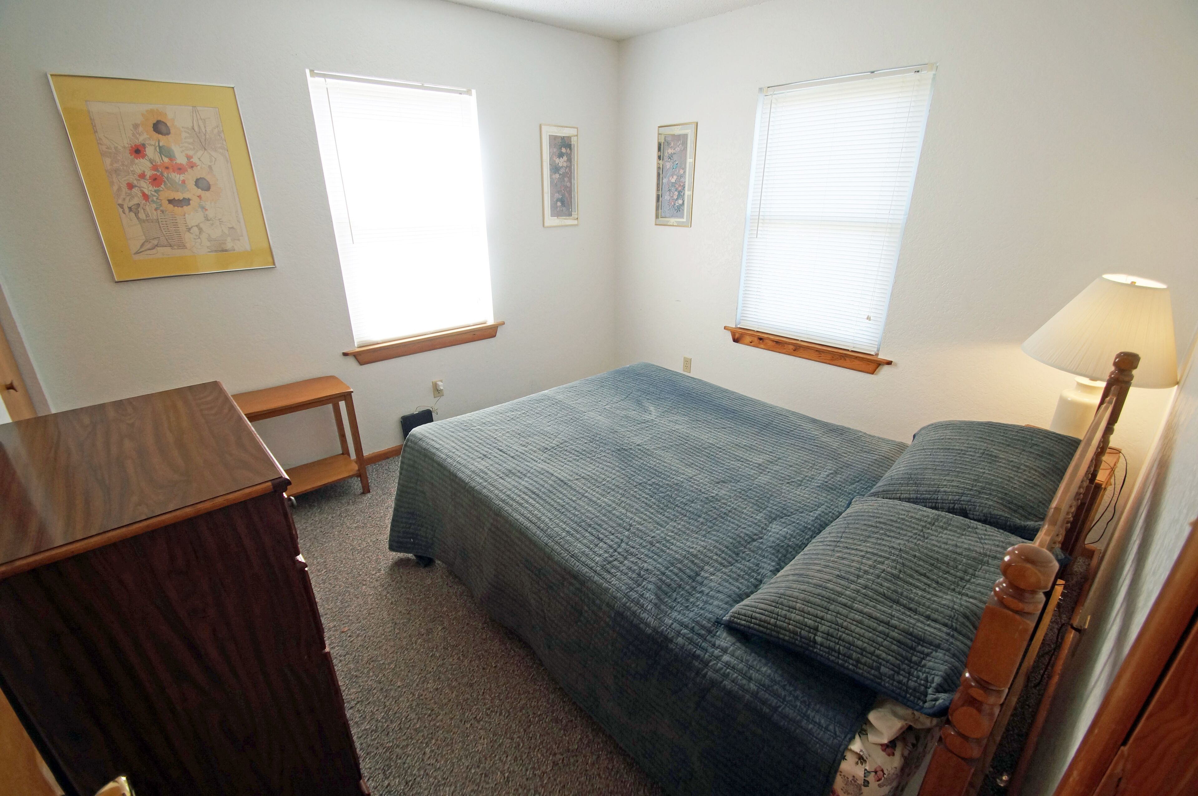 Un dormitorio con cama, escritorio y lámpara.