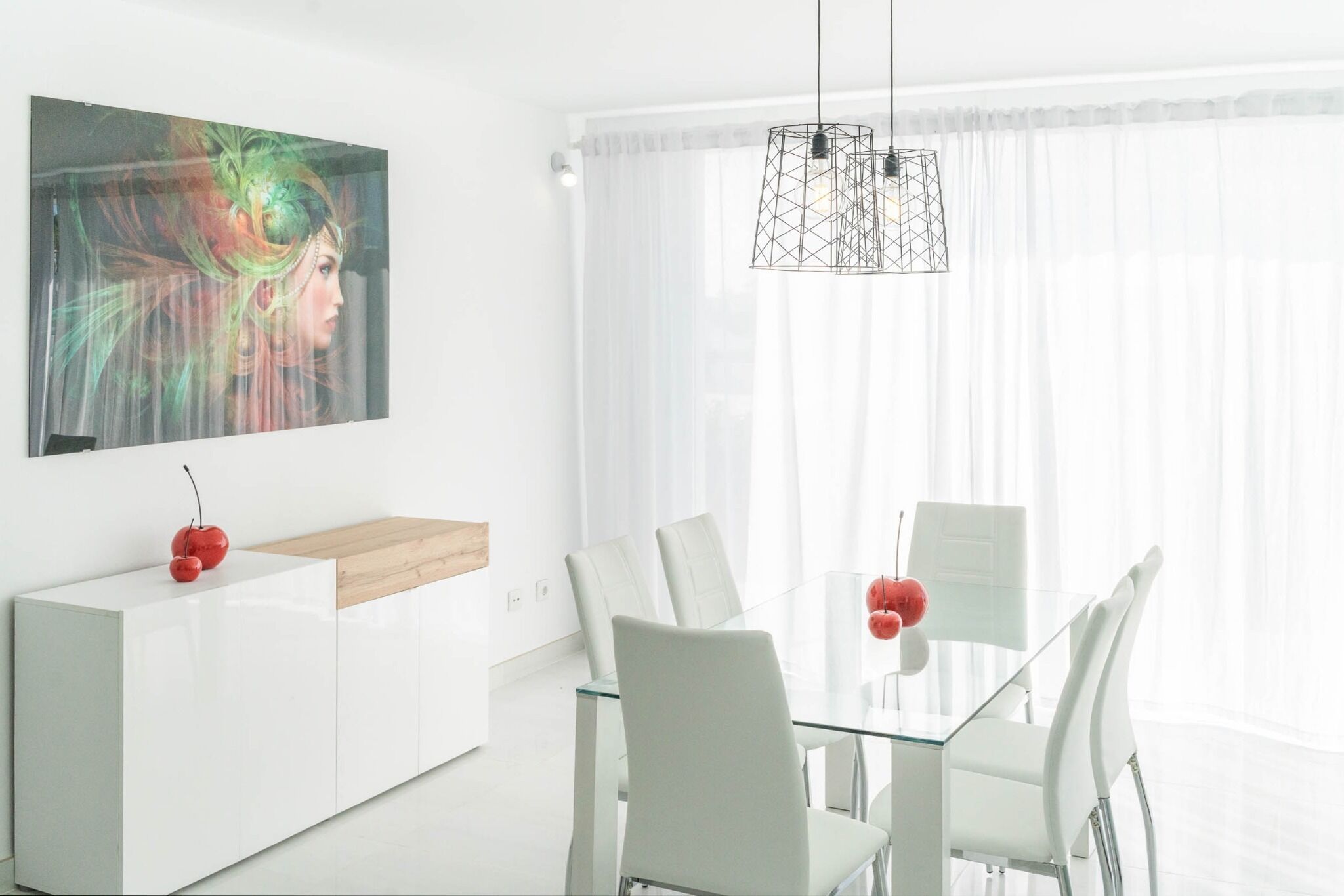 Ein moderner Essbereich mit Glastisch, weißen Stühlen, einem weißen Schrank und einer Pendelleuchte.