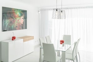 A modern dining area with a glass table, white chairs, a white cabinet, and a pendant light. - VILLA DREAMS. RELAX WITH HEATED POOL, (Playa Blanca)