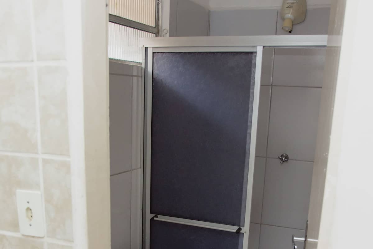 A bathroom with a toilet, a shower enclosure, and a tiled floor.