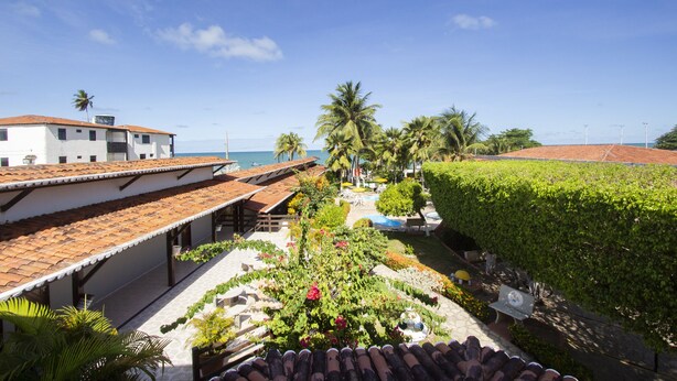 Ein Innenhof mit Pool, Palmen und Blick aufs Meer.