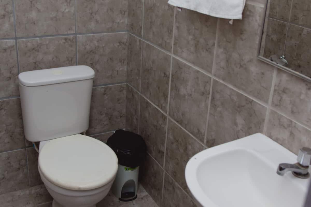 A bathroom with a toilet, sink, and tiled walls.