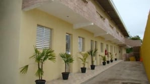 A building with a row of windows and potted plants along the side. - Pousada Aconchego (Peruíbe)