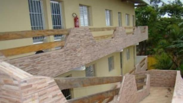 A multi-level building with a stone facade and wooden railings. - Pousada Aconchego (Peruíbe)