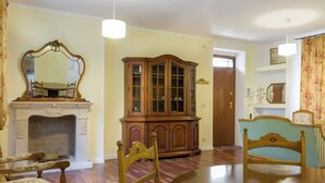 A dining room with a fireplace, wooden cabinet, and two chairs.