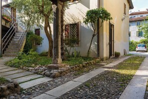 A residential building with a stone pathway, a staircase, and a car parked in the driveway.