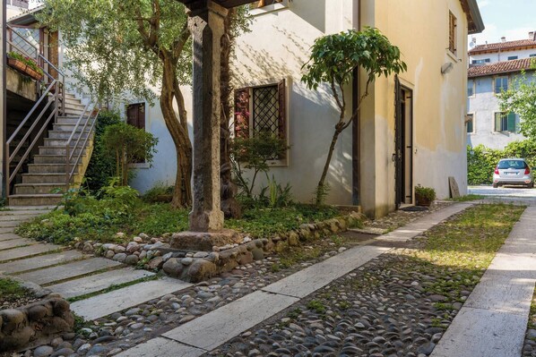Un edificio residencial con un camino de piedra, una escalera y un coche en la entrada.