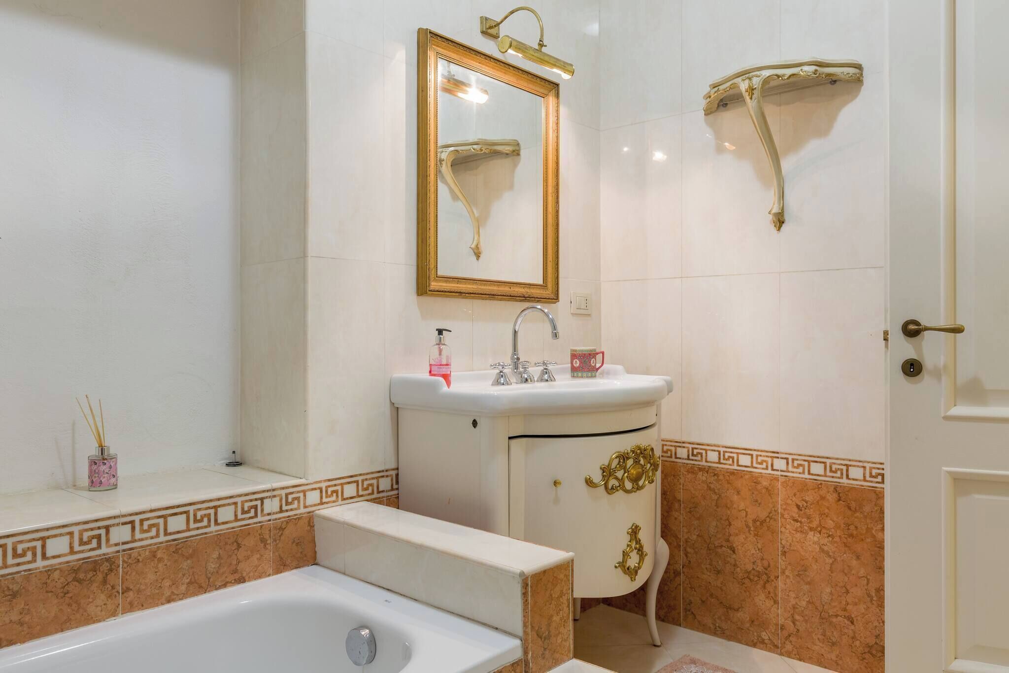 Une salle de bain avec une baignoire, un lavabo, un miroir et une porte.