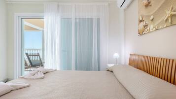 Habitación de hotel con una cama grande, un balcón con una silla y una decoración de conchas marinas y estrellas de mar en la pared.