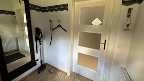 A hallway with a mirror, a vacuum cleaner, a door with a decorative handle, and a small sign on the wall.