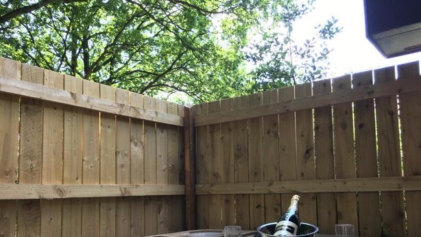 A hot tub with a champagne bottle and glasses, surrounded by a wooden fence. - Bluebell 16 with Hot Tub (Carmarthen)
