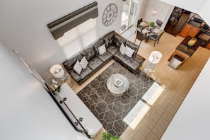 A modern living room with a sectional sofa, a glass coffee table, and a dining area with a chandelier.