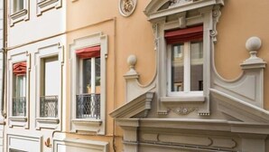 En byggnadsfasad med utsmyckade arkitektoniska detaljer, inklusive dekorativa fönsterramar och en balustrad.