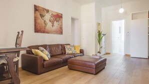 Un salón amplio con un sofá de cuero marrón, una mesa de centro de madera y un gran mapa mundial en la pared.