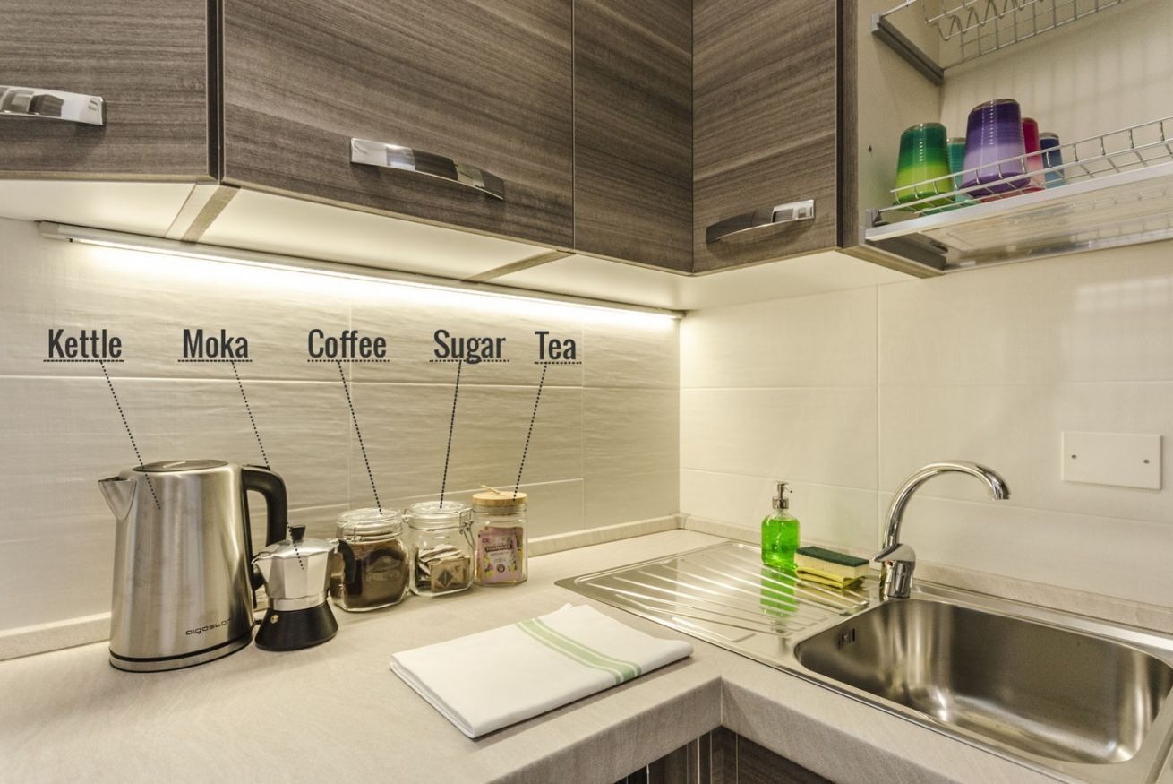 Een moderne keuken met een waterkoker, mokapot, koffiezetapparaat, suiker en thee.