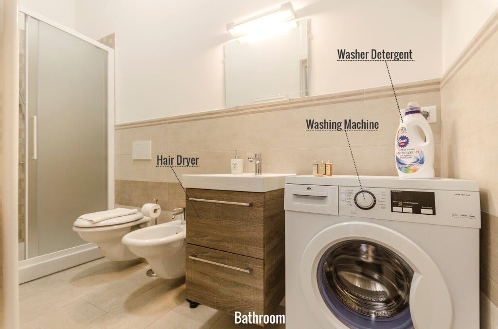 Un baño con secador de pelo, lavadora y retrete.