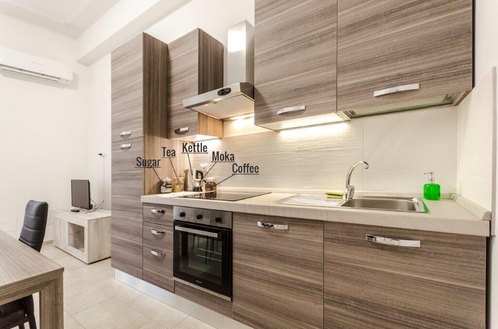 A modern kitchen with wooden cabinets, a built-in oven, and a stainless steel sink.