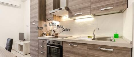 A modern kitchen with wooden cabinets, a built-in oven, and a stainless steel sink.