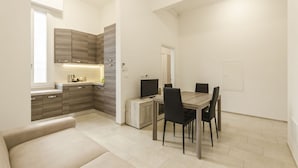 A compact living space with a kitchenette, a dining area with a table and chairs, and a sofa. - S.Felice apartments (Bologna)