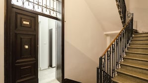 A staircase with ornate metal railings and a dark wooden door with a nameplate. - S.Felice apartments (Bologna)