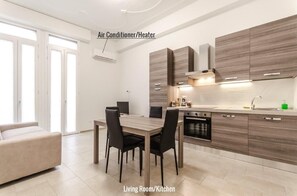 A modern kitchen with wooden cabinets, a dining area with a table and chairs, and an air conditioner/heater on the wall. - S.Felice apartments (Bologna)