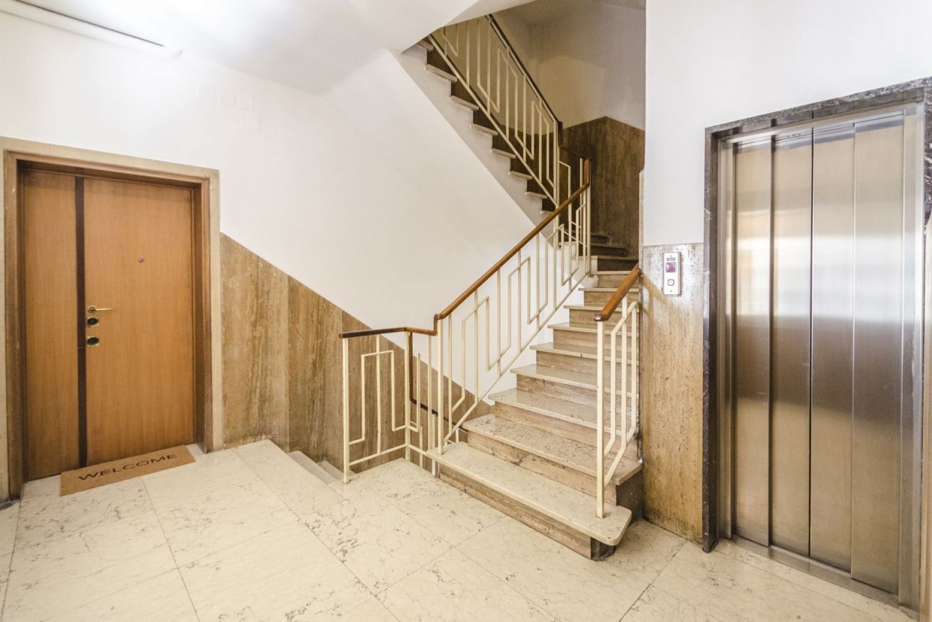 A staircase with a wooden door and a metallic elevator.
