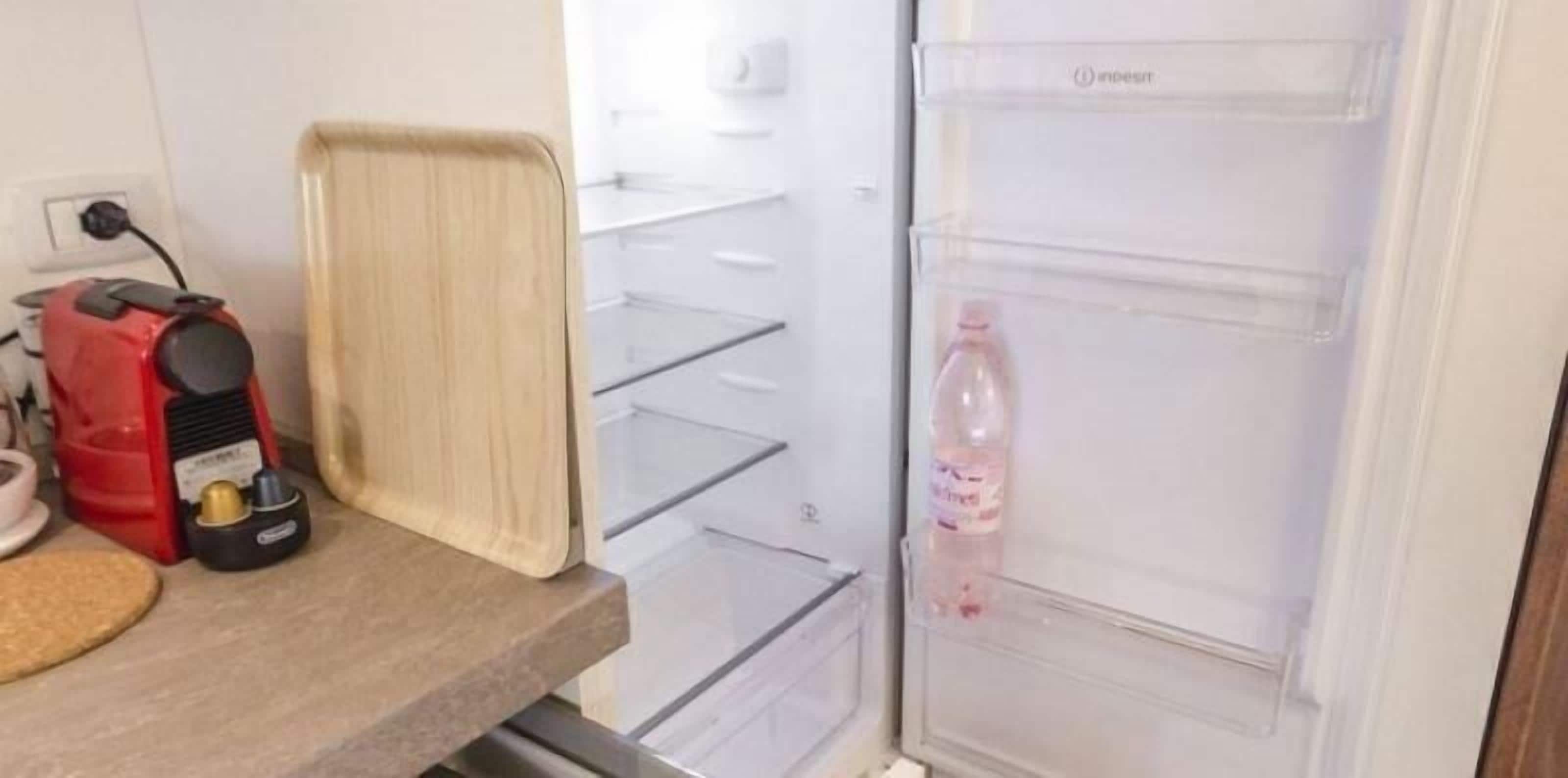 Een keuken met een koelkast, een koffiezetapparaat en een waterfles.