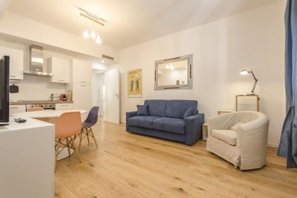 Una sala de estar moderna con un sofá, un sillón y un comedor con sillas y una mesa.