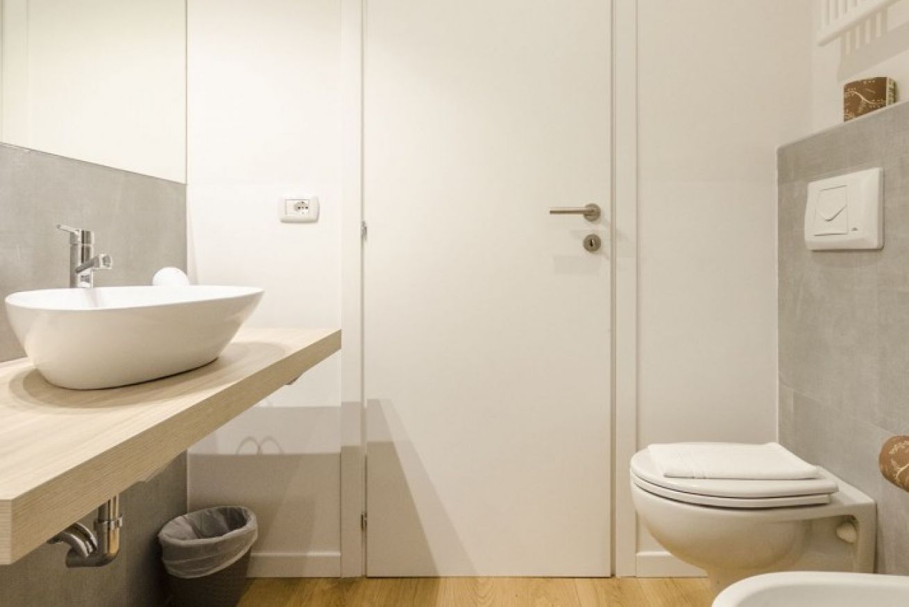 Et moderne badeværelse med hvid vask, toilet og bruseområde.