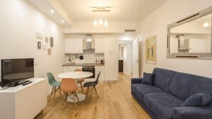 A modern living space with a dining area, kitchenette, and a sofa. - Il Campo Apartments (Bologna)