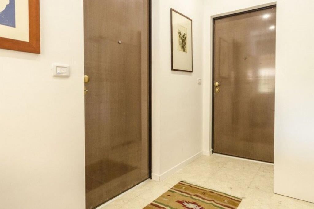 A hallway with two closed doors, a framed picture on the wall, and a patterned rug on the floor.