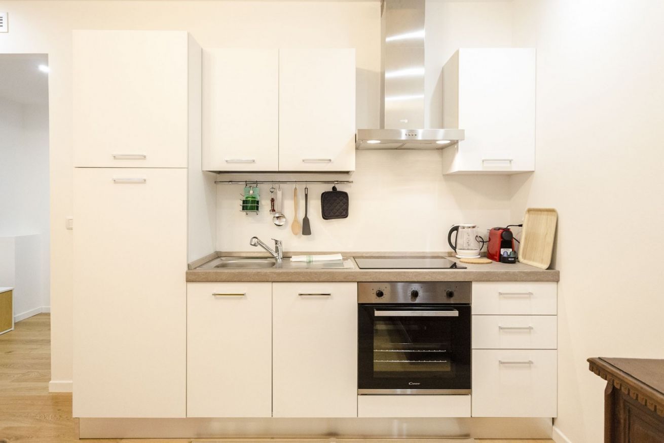 A modern kitchen with white cabinets, a stainless steel oven, and a sink.