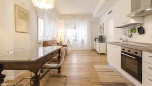 A modern kitchen with white cabinets, a stainless steel oven, and a dining area with a glass table and chairs. - Il Campo Apartments (Bologna)