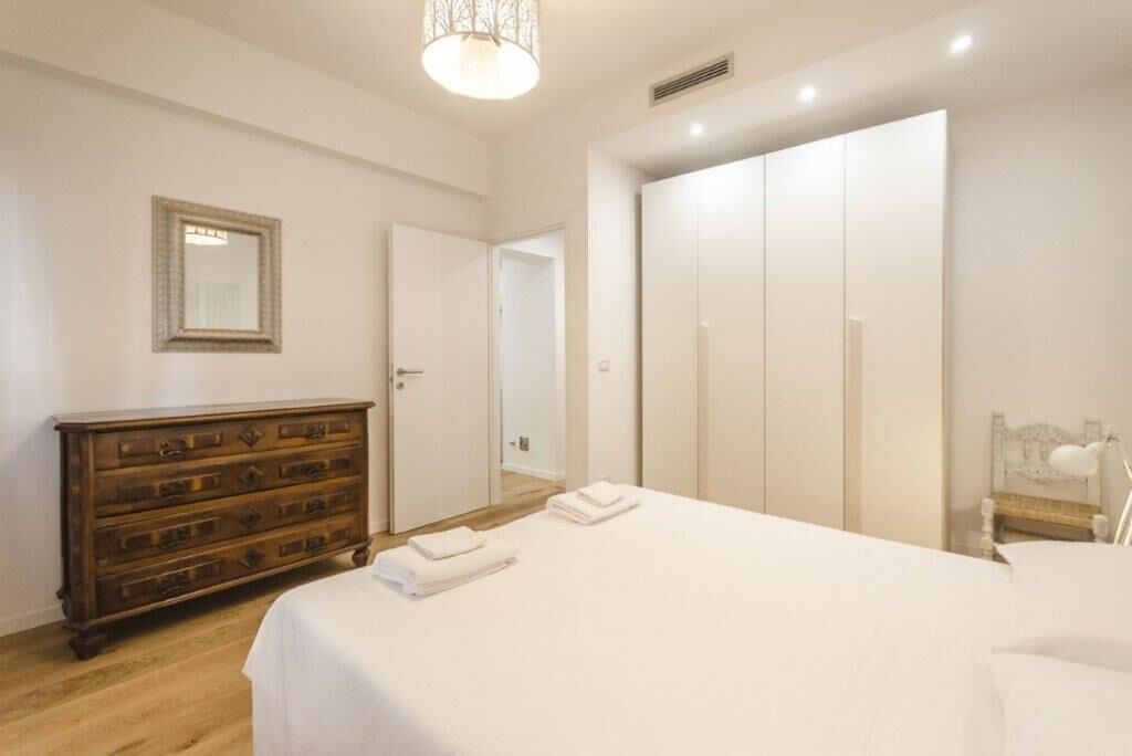 A bedroom with a bed, a dresser, a mirror, and a wardrobe.