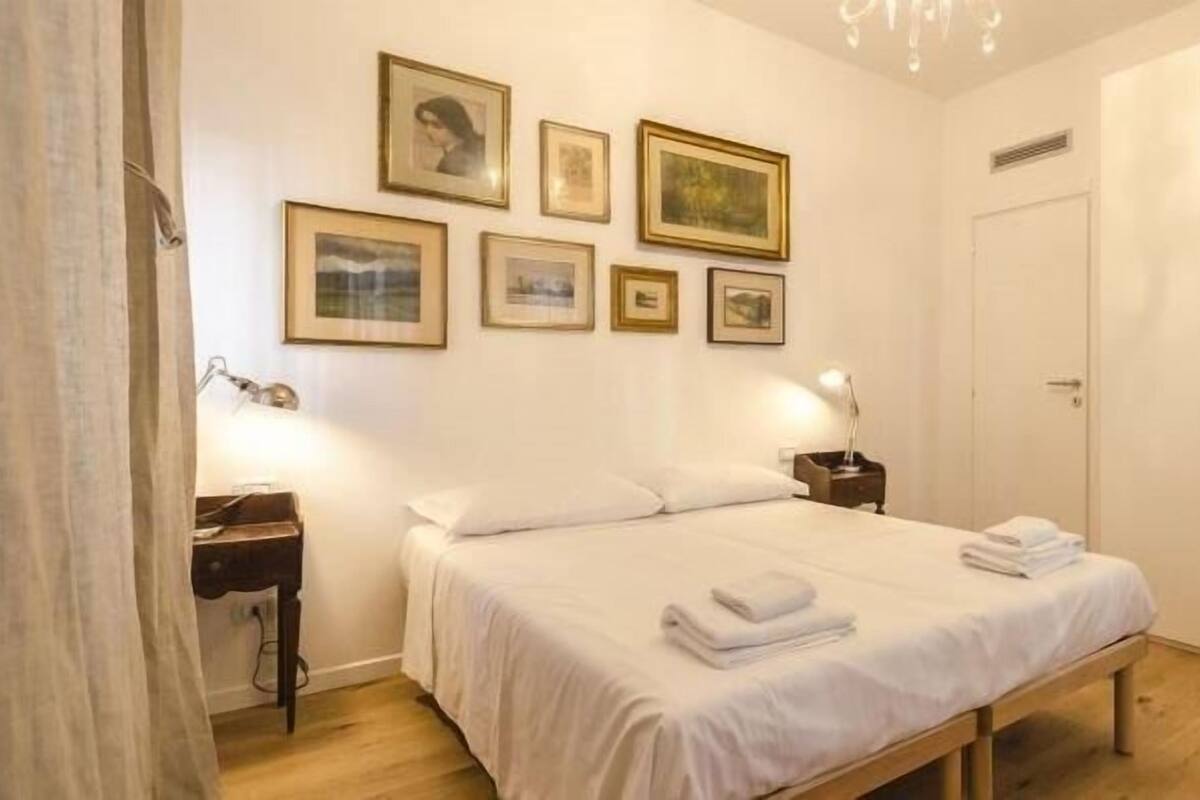 Una camera da letto con un letto, comodini, un armadio e quadri appesi al muro.