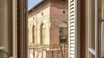 Vue depuis un balcon ouvert sur un bâtiment historique doté d’arcatures et d’une tour.