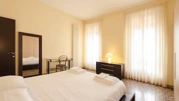 Une chambre d’hôtel avec un lit bien fait, une table de chevet avec une lampe, une chaise et une armoire.