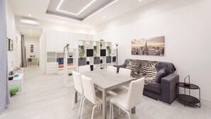 Ein modernes Wohnzimmer mit Esstisch, weißen Stühlen, einem grauen Sofa und einer Zebra-Decke.