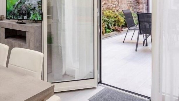 Ein modernes Wohnzimmer mit einer Schiebeglastür, die auf eine Terrasse im Freien führt.