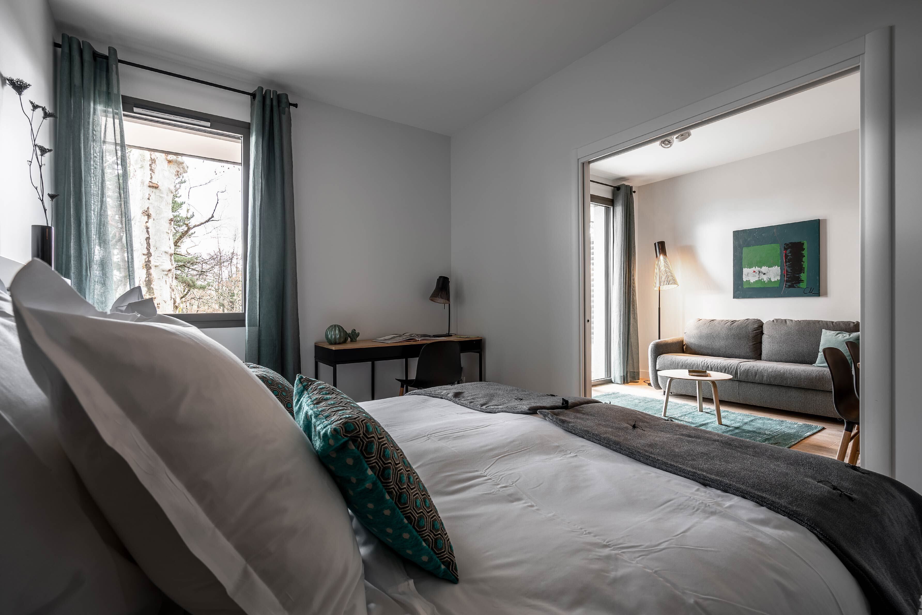 Una camera da letto moderna con un letto grande, una scrivania e un divano nella zona living adiacente.