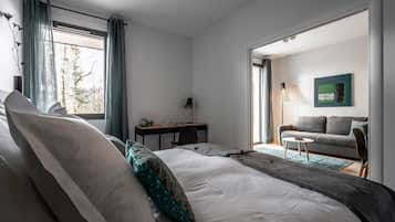 Una camera da letto moderna con un letto grande, una scrivania e un divano nella zona living adiacente.