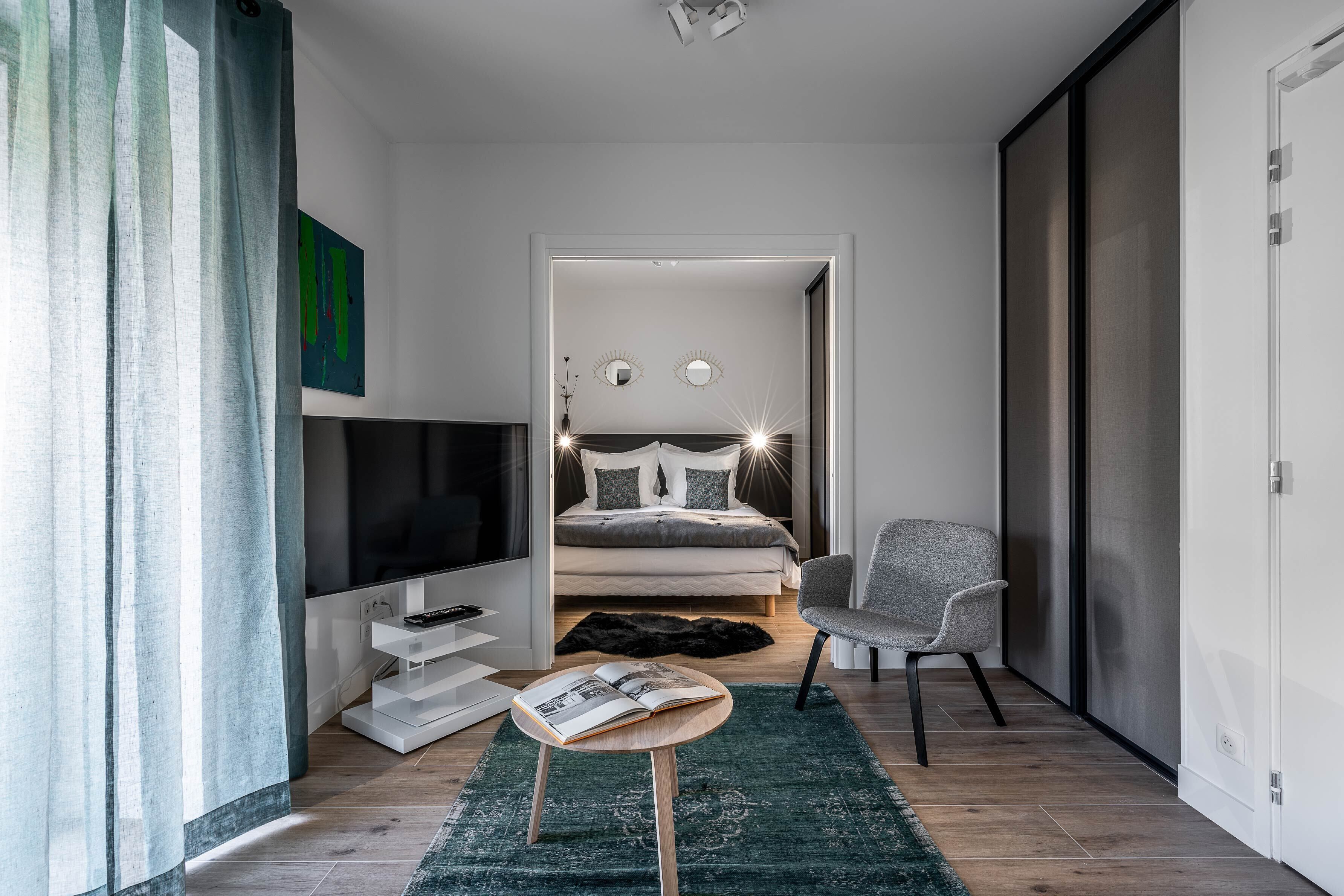 Une chambre à coucher moderne avec un lit, une télévision et un fauteuil.