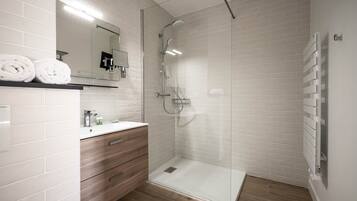 A modern bathroom with a glass-enclosed shower, a wooden vanity, and a white tiled shower area.
