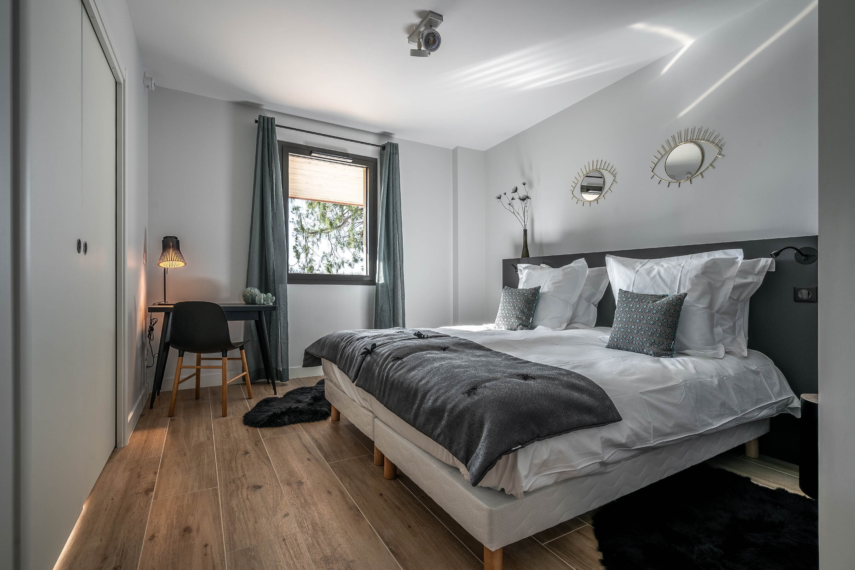 A modern bedroom with a bed, desk, and chair.