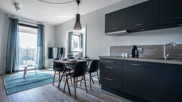 A modern kitchen with dark cabinets, a wooden countertop, and a dining area with a table and chairs.
